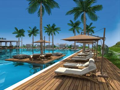 A luxurious pool area with sun loungers, palm trees, and clear blue sky at a vacation spot.