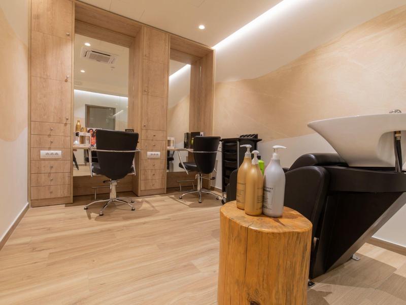 Nowoczesny salon fryzjerski z drewnianą okładziną, myjnią i fotelami fryzjerskimi.