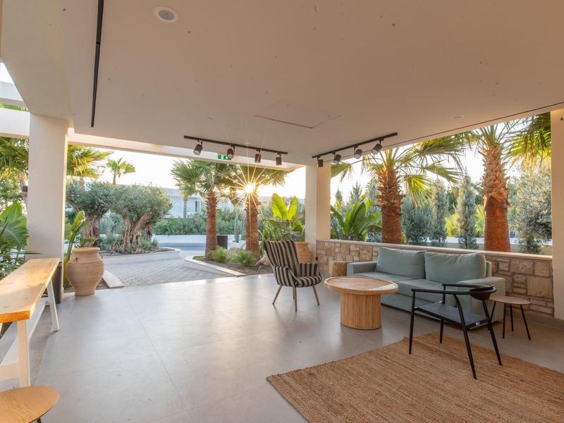 Otwarta przestrzeń salonowa z miejscami do siedzenia i widokiem na palmy i basen
