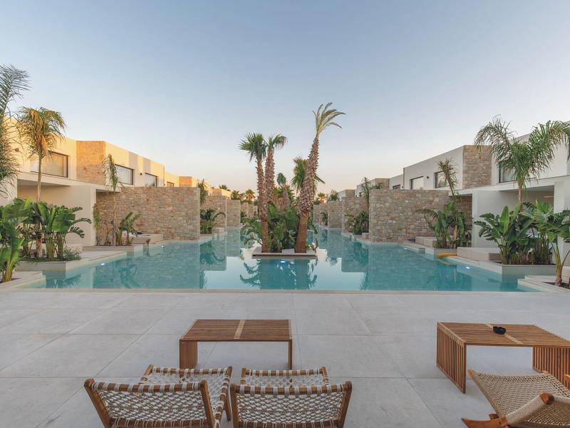 Nowoczesny basen z roślinami i wygodnymi krzesłami w ośrodku hotelowym.