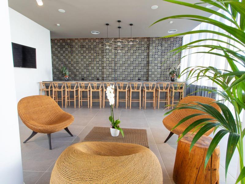 Nowoczesna przestrzeń z wygodnymi miejscami do siedzenia, długim stołem i zieloną rośliną.