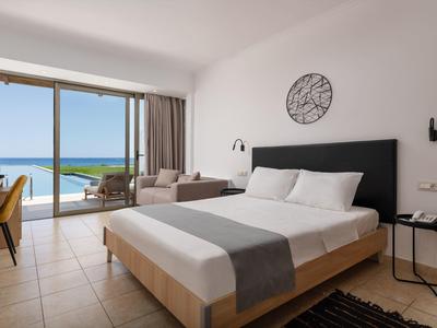 Moderne hotelkamer met groot bed, balkon met uitzicht op zee en comfortabele zithoek.