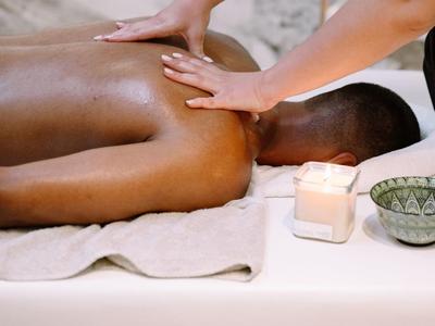 Persoon krijgt een rugmassage op een wit tafelblad met kaars en kom in de buurt.
