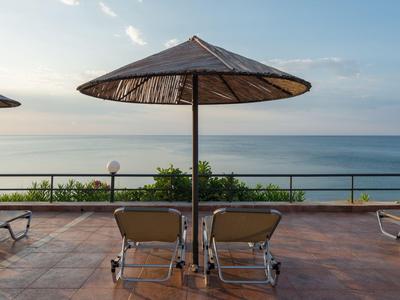 Dwa leżaki pod parasolem z widokiem na morze i niebo.