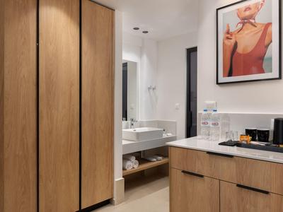 Moderne badkamer met houten kasten, wastafel en stijlvolle wanddecoratie.