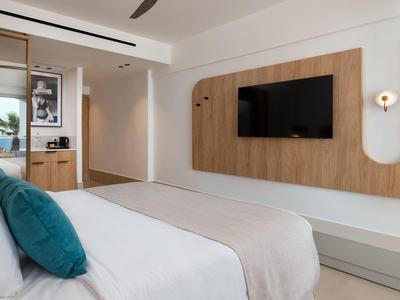 Modern hotelkamer met bed, tv aan houten paneel en inrichting in lichte, vriendelijke stijl.