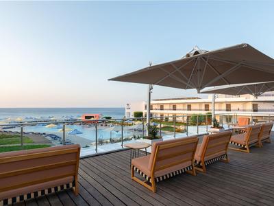 Terrazza con mobili lounge e ombrellone con vista sul mare sotto un cielo sereno.