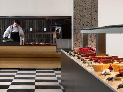 Buffet con dolci e uno chef dietro il bancone in un ristorante.