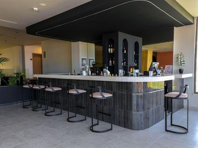 Moderní hotelový bar s sedmi stoličkami a elegantním černým pultem.