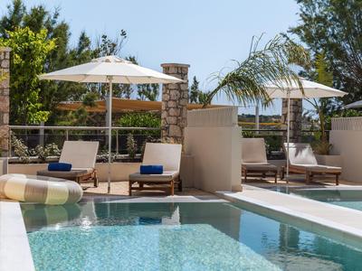 Moderner Hotelpool mit Sonnenliegen und weißen Sonnenschirmen im Freien.