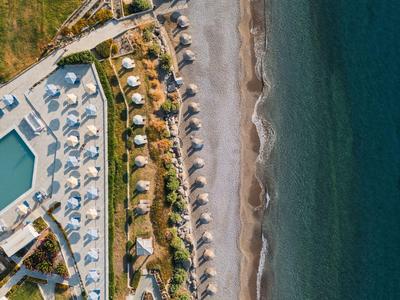 Letecký pohled na plážový resort s řadami slunečníků a přilehlým mořem.