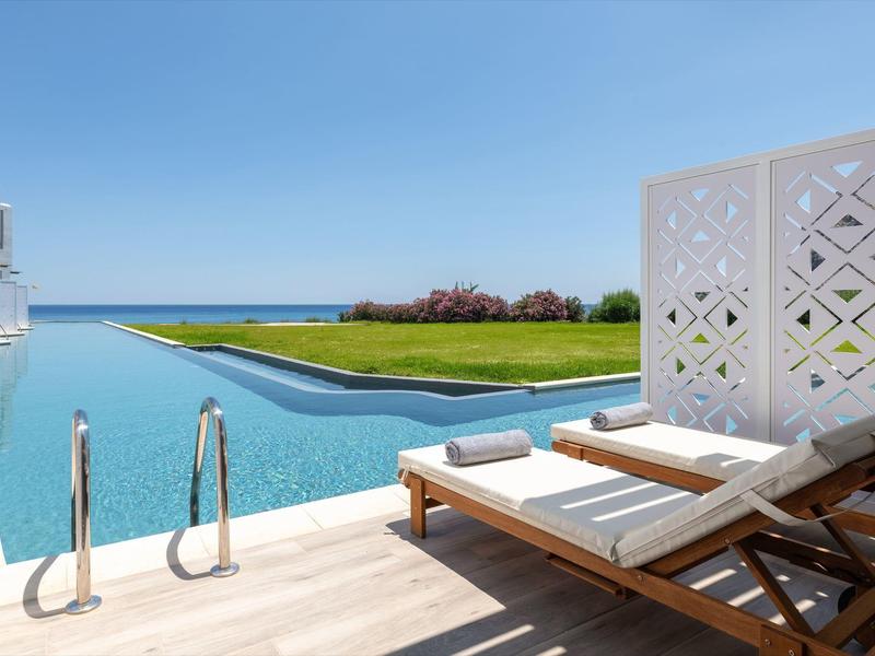 Ligbedden bij het zwembad met uitzicht op de oceaan en een heldere hemel bij een luxe hotel.