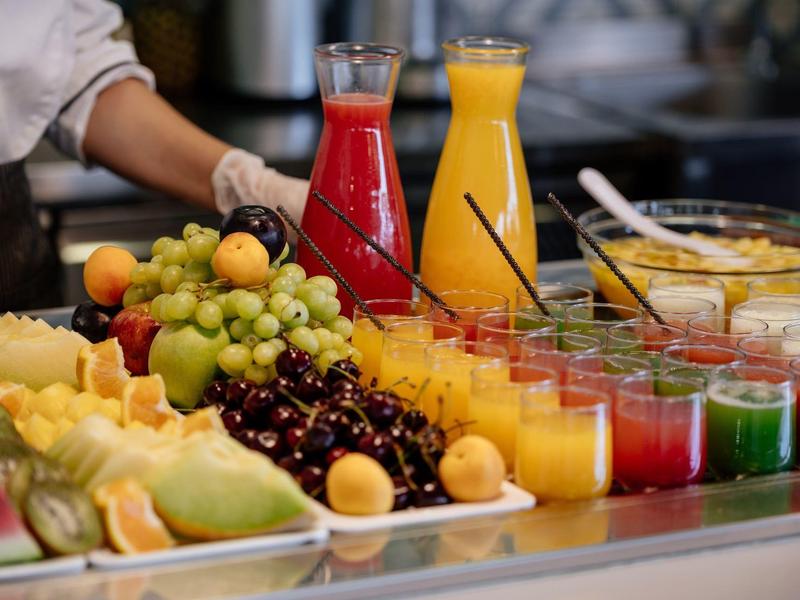 Buffet met vers fruit, kleurrijke sappen en glazen op een binnenbalie.