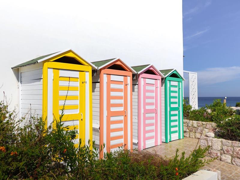 Kleurrijke strandhuisjes met geel, roze en groen ontwerp vlak bij de zee.