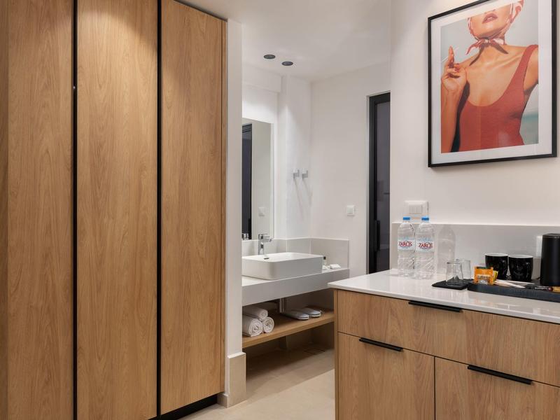 Moderne badkamer met houten kasten, wastafel en stijlvolle wanddecoratie.