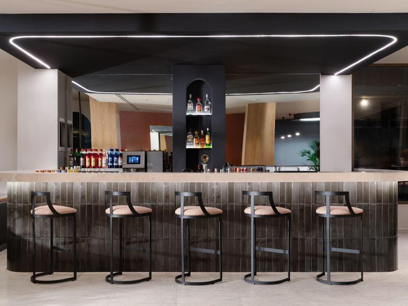 Moderne hotelbar met vijf barkrukken en stijlvolle verlichting.