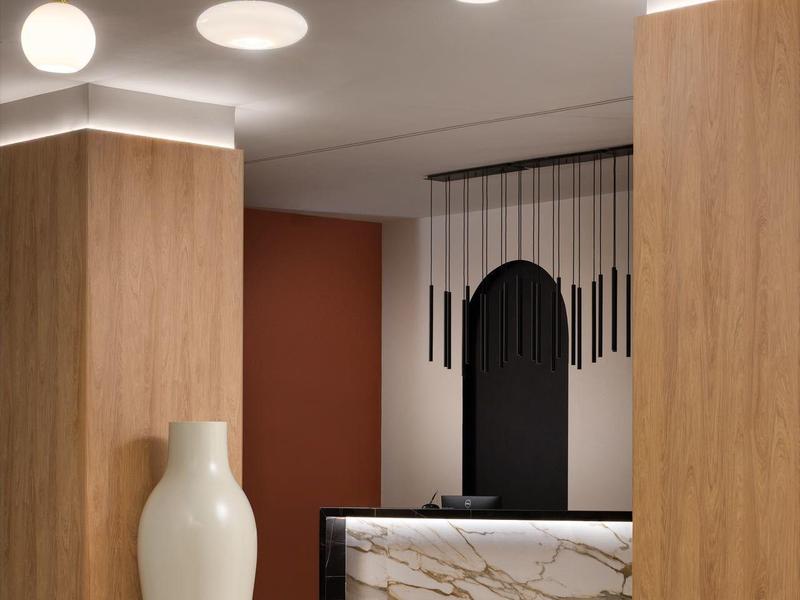 Moderne hotel lobby met hanglampen, marmeren balie en grote witte vaas.