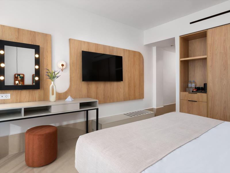 Modern hotelkamer met tweepersoonsbed, wand-tv en bureau met spiegel.