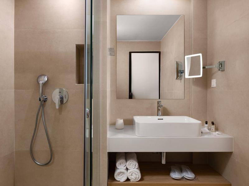 Moderne badkamer met wastafel, spiegel, handdoeken en inloopdouche.