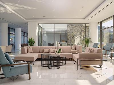 Jasna przestrzeń wypoczynkowa z nowoczesną sofą, fotelami i dużymi oknami w hotelu.