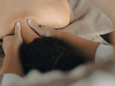 Persona che riceve un massaggio alla schiena in un ambiente rilassato con toni caldi.