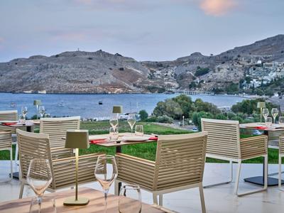 Terrazza con sedie e tavoli con vista su una baia e colline sullo sfondo.