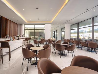 Sala da pranzo moderna con sedie marroni e grandi finestre con vista sulle montagne.