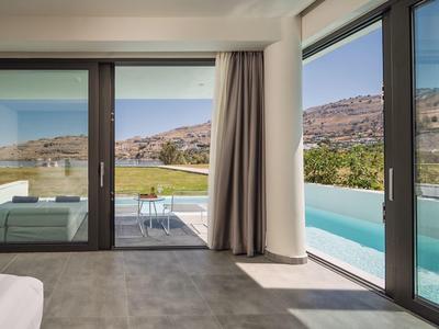 Camera d'hotel moderna con grandi finestre in vetro con vista sulla piscina e sulle colline.