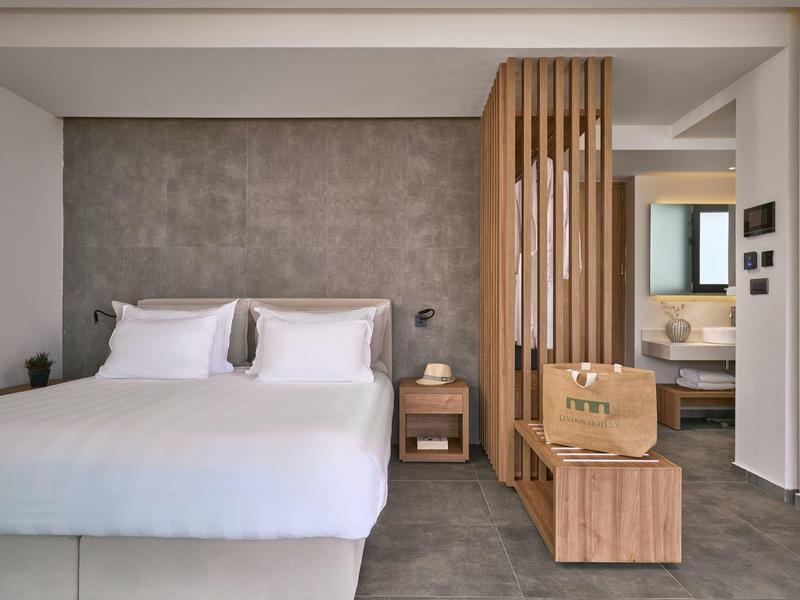 Camera d'hotel moderna con letto matrimoniale, comodino e dettagli in legno.