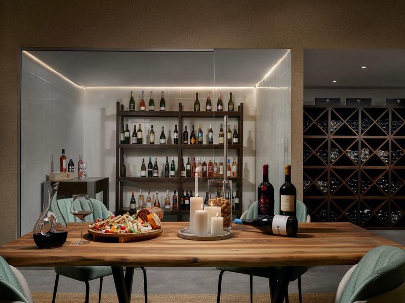 Accogliente zona pranzo con tavolo in legno, bottiglie di vino e snack in un ambiente moderno ed elegante.