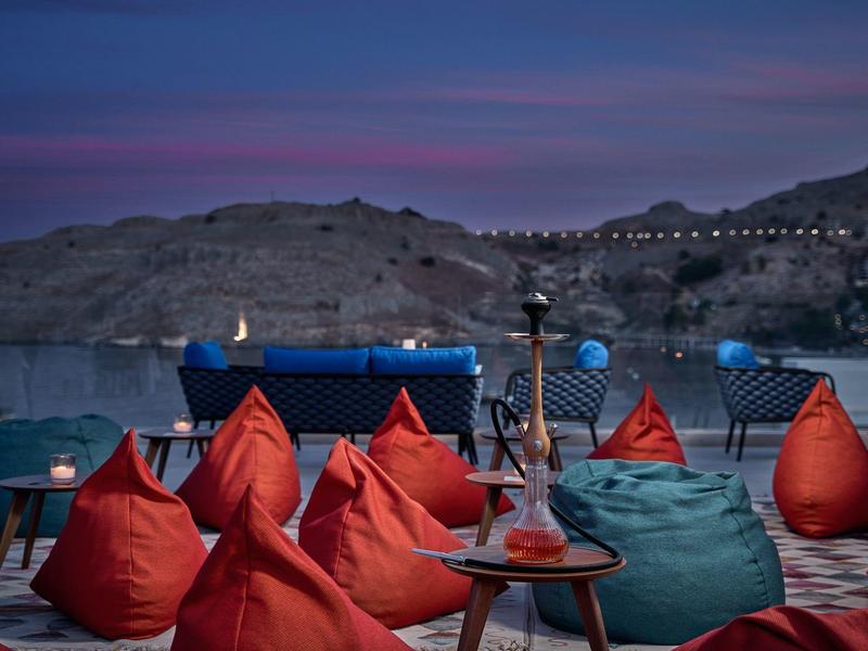 Posti a sedere accoglienti con pouf colorati, vista sulle montagne e cielo serale.
