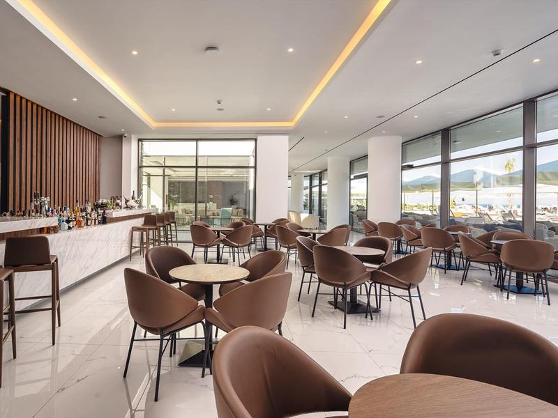 Sala da pranzo moderna con sedie marroni e grandi finestre con vista sulle montagne.