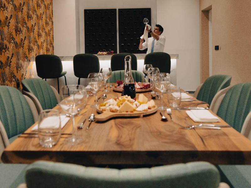 Lungo tavolo in legno apparecchiato con snack e sedie in una sala da pranzo elegante.