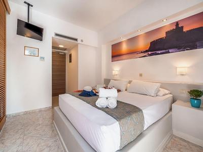 Habitación de hotel moderna con cama grande, arte en la pared y televisor montado en la pared.