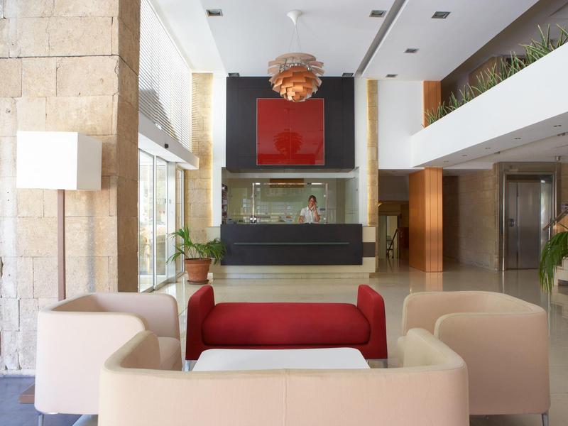 Modernes Wohnzimmer mit roten und beigen Sofas, Kamin, Glaswänden und orangefarbener Deckenlampe.