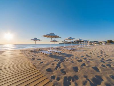 Strand mit Sonnenliegen und Sonnenschirmen bei Sonnenaufgang am Meer