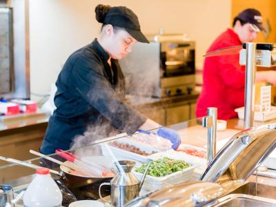 Cocina en un hotel con chefs preparando platos humeantes.