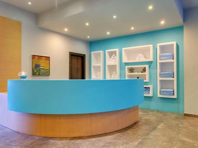 Recepción moderna de hotel con mostrador redondo bicolor y pared pintada de azul.