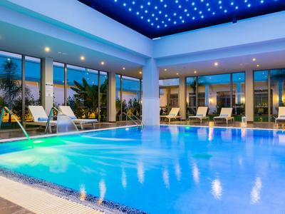 Piscina interior moderna con iluminación azul y grandes ventanales en un hotel