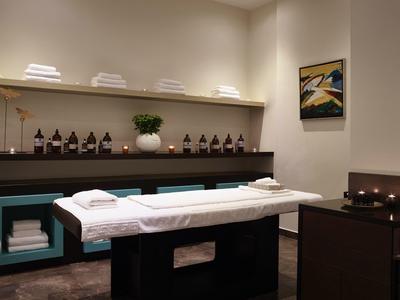 Sala de spa tranquila con camilla, toallas, velas encendidas y decoración minimalista.