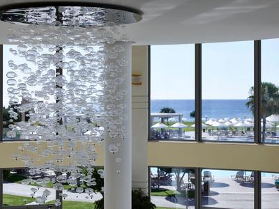 Lámpara moderna en un hotel con vista a una piscina y el mar a través de grandes ventanas.