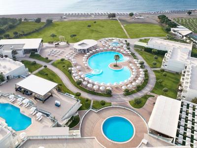 Luftaufnahme eines Hotelresorts mit mehreren Pools und einer grünen Küstenlandschaft im Hintergrund.