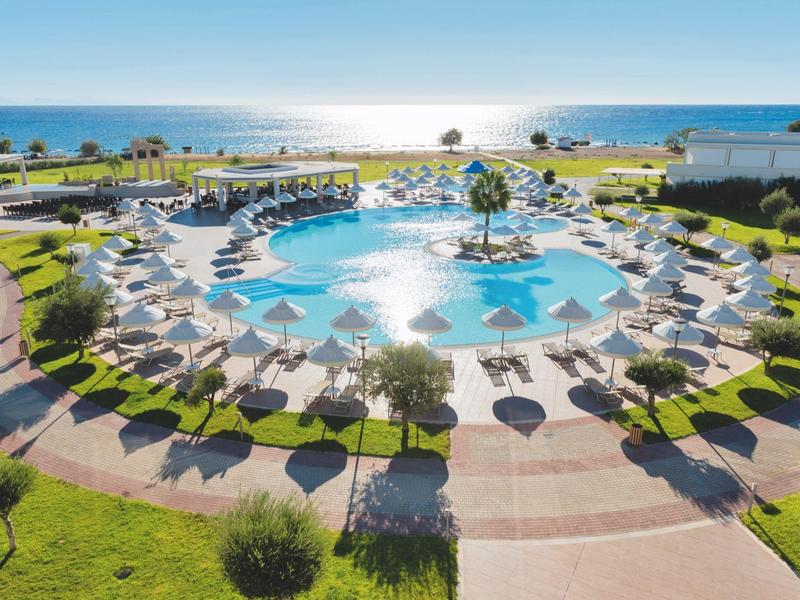 Gran piscina redonda con sombrillas y tumbonas junto a la vista al mar en un hotel.