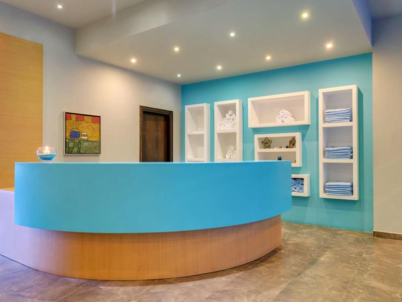 Recepción moderna de hotel con mostrador redondo bicolor y pared pintada de azul.