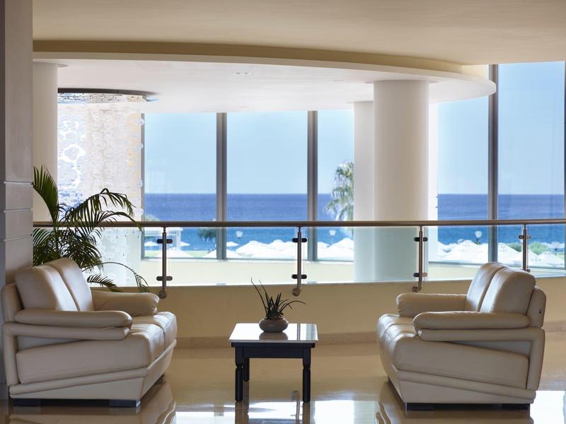 Área de descanso moderna con sillones de cuero frente a grandes ventanas con vista al mar en el hotel.