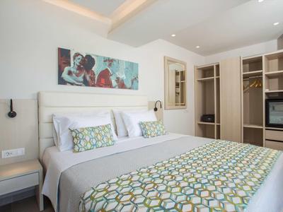 Nowoczesny pokój hotelowy z łóżkiem podwójnym, kolorową narzutą i przestronną szafą.