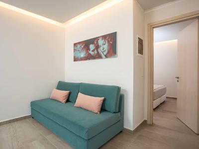 Nowocześnie urządzone pomieszczenie z zieloną sofą, poduszkami dekoracyjnymi i widokiem na sypialnię.