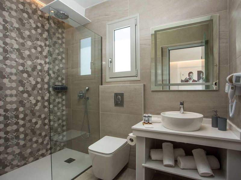 Nowoczesna łazienka z prysznicem, toaletą, umywalką i ręcznikami w pokoju hotelowym.