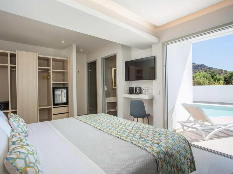 Nowoczesny pokój hotelowy z łóżkiem king-size, otwartą szafą i dostępem do tarasu z widokiem na basen.