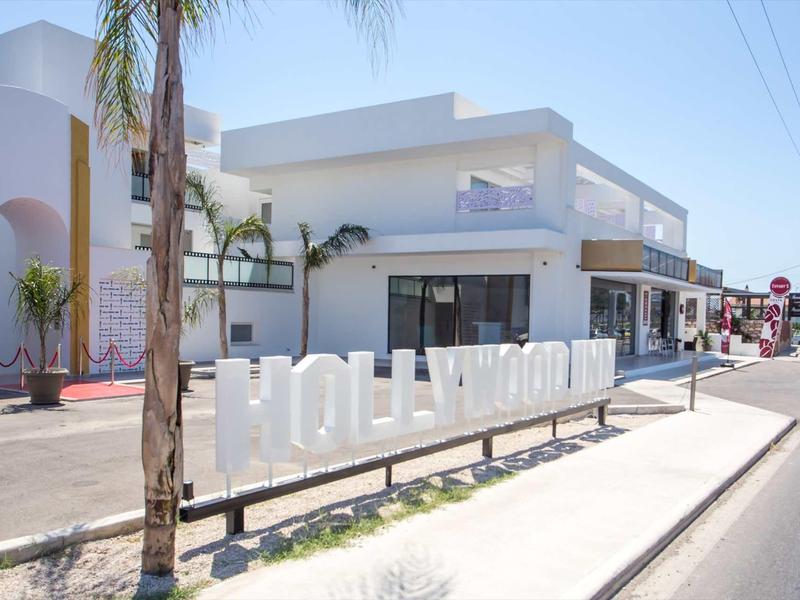 Białe litery Hollywood obok nowoczesnego budynku przy słonecznej ulicy